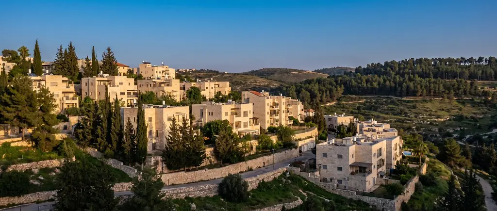 Stone houses stepping down a green slope in Mevaseret Zion